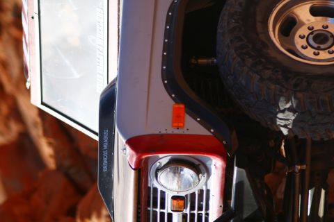1979 Ford Bronco - A close-up, upside-down view of the front fender and headlight area of a modified off-road vehicle, possibly a Ford Bronco, with a spare ti…