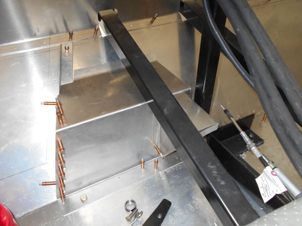 Interior view of a vehicle under construction, showing metal panels, wiring, and structural components.