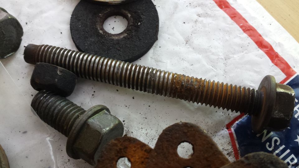 Close-up of rusty bolts and washers on a white surface.