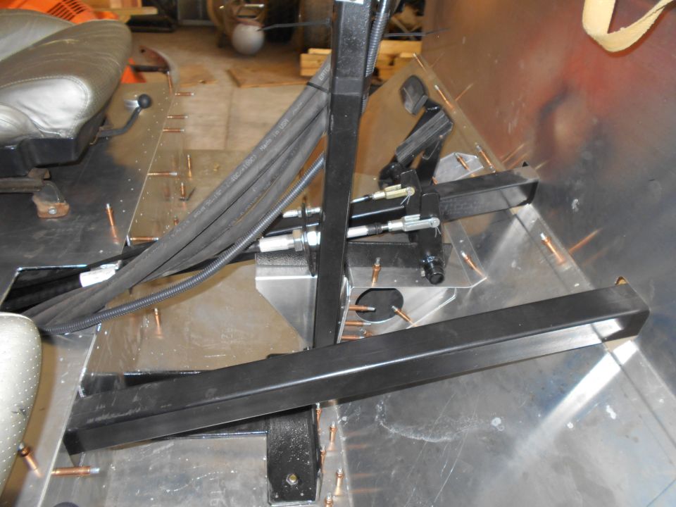 Vehicle interior floor with hydraulic lines and metal supports.