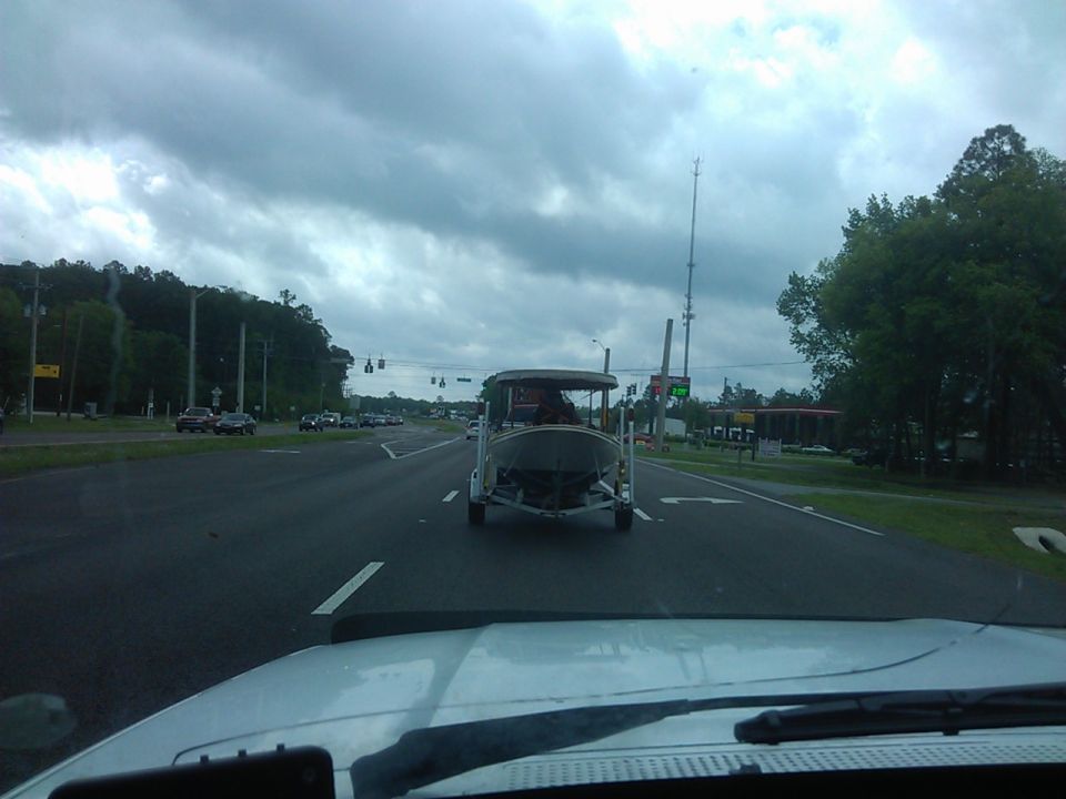 A boat on a trailer being towed on a road.