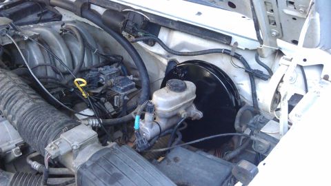1994 Ford Bronco - The engine bay of a 1994 Ford Bronco shows the brake master cylinder, brake booster, and air intake system.