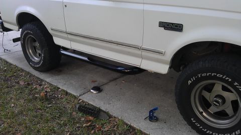 1994 Ford Bronco - The side view of a white Ford Bronco shows a chrome trim piece along the lower body and a black side step. The vehicle is parked on a concr…
