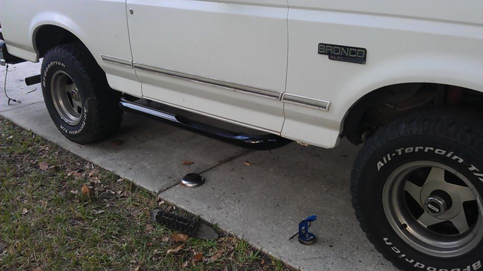 White Ford Bronco side view with chrome trim and black side step.