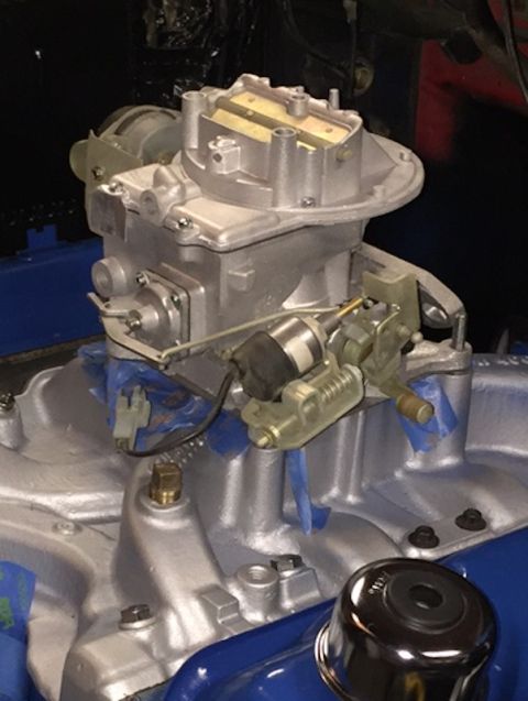 1978 Ford Bronco - A silver-painted carburetor is mounted on a silver-painted intake manifold, which is part of a vehicle engine. Blue tape is used to mask of…