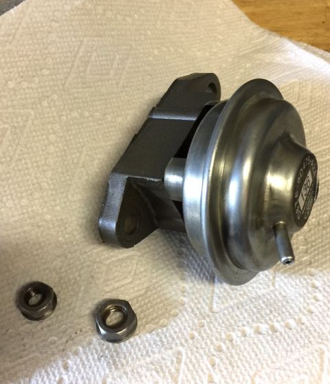 1978 Ford Bronco - A turbocharger wastegate actuator with two nuts rests on a white paper towel. The actuator is made of metal and has a circular diaphragm ho…