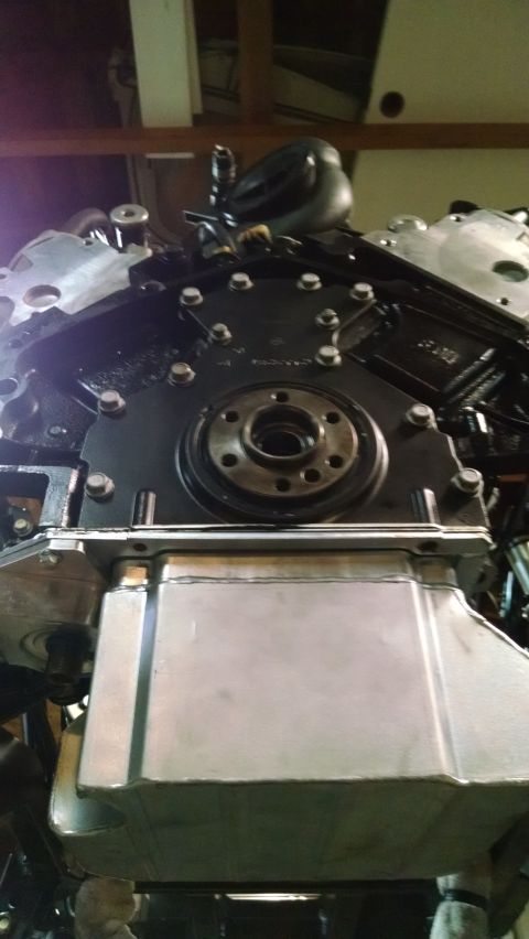 1985 Jeep CJ7 - Close-up view of the rear of an engine, showing the flywheel housing and oil pan. The engine appears to be a V8 with black painted componen…