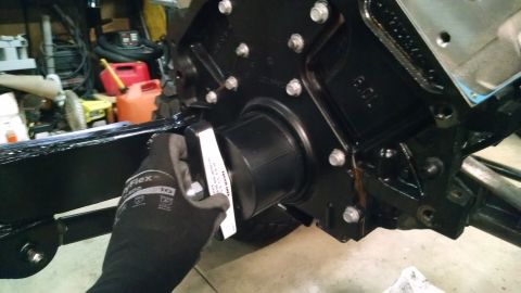 1985 Jeep CJ7 - A gloved hand is holding a black plastic part with a white sticker against the black engine block of a vehicle. The engine block is bolted…