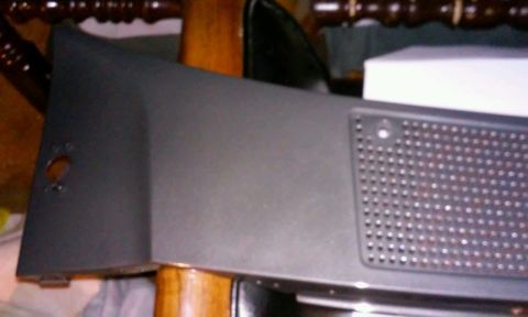 1986 Ford Bronco - A dark gray plastic panel with a circular cutout on the left and a perforated section on the right is shown at an angle. The panel appears…