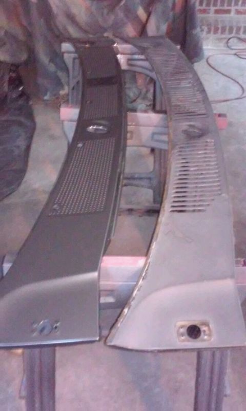 1986 Ford Bronco - Two black plastic cowl vents, one with a perforated section and the other with horizontal slats, are displayed side-by-side on sawhorses.
