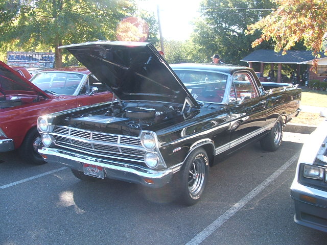 Black 1972 Ford Ranchero with hood open, engine visible, parked outdoors.