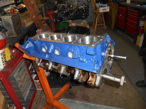 1972 Ford Bronco - A blue Ford V8 engine block is mounted on an orange engine stand. The crankshaft is visible through the bottom of the block, and a bolt is…