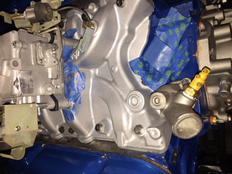 1978 Ford Bronco - A close-up view of a silver-painted engine intake manifold with blue painter's tape covering a section. A yellow temperature sensor is visi…