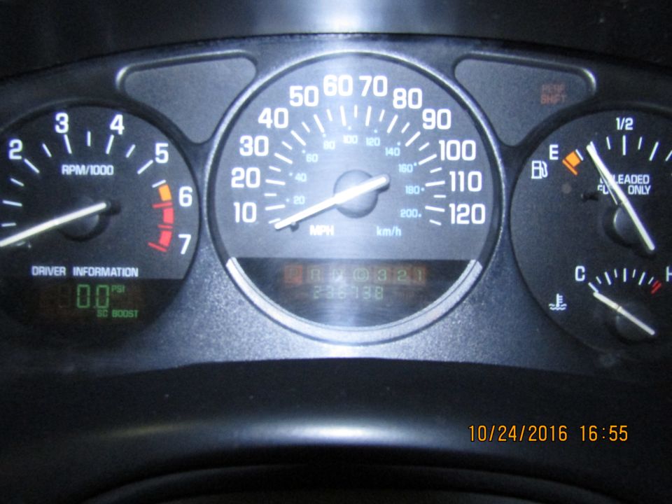 Car dashboard with speedometer, tachometer, fuel gauge, and digital display.