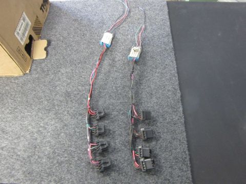 Two wiring harnesses with multiple connectors on a grey carpet.