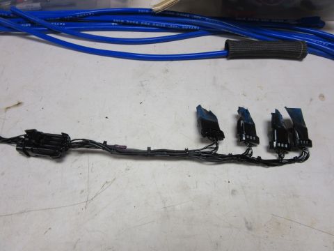 Black electrical wiring harness with connectors and blue spark plug wires.