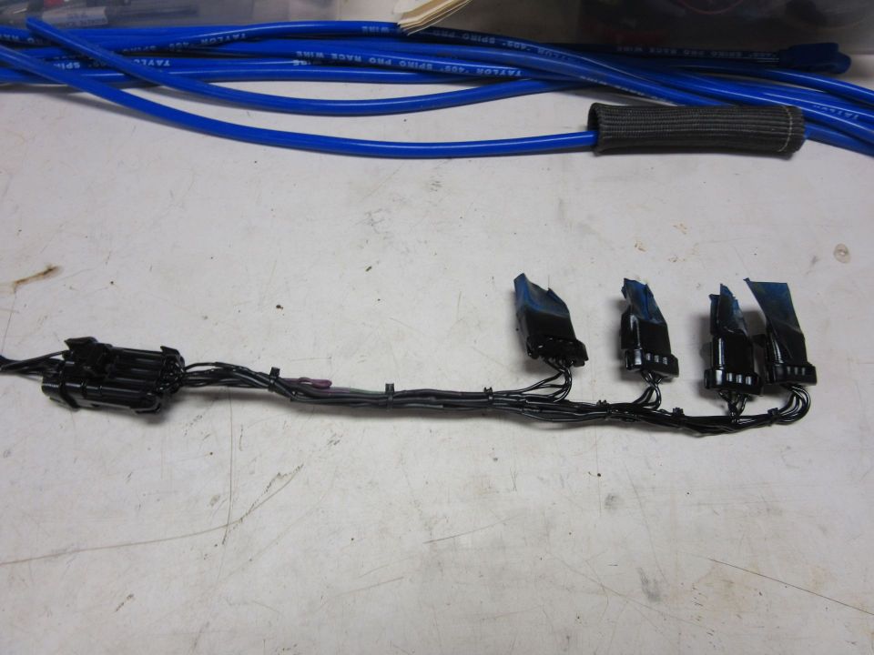 Black electrical wiring harness with connectors and blue spark plug wires.