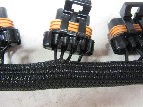 Braided black wire loom with multiple black electrical connectors with orange seals.