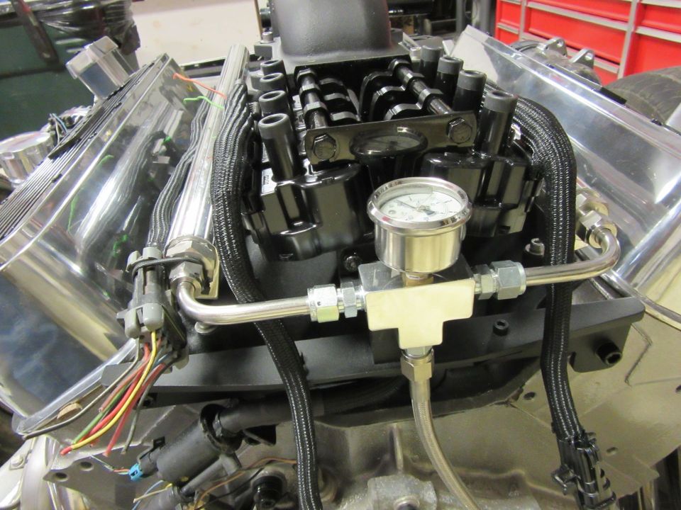 Modified V8 engine with polished valve covers, fuel lines, and pressure gauge.