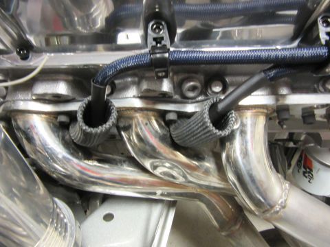 Polished exhaust manifold with heat sleeves on spark plug wires on a V8 engine.
