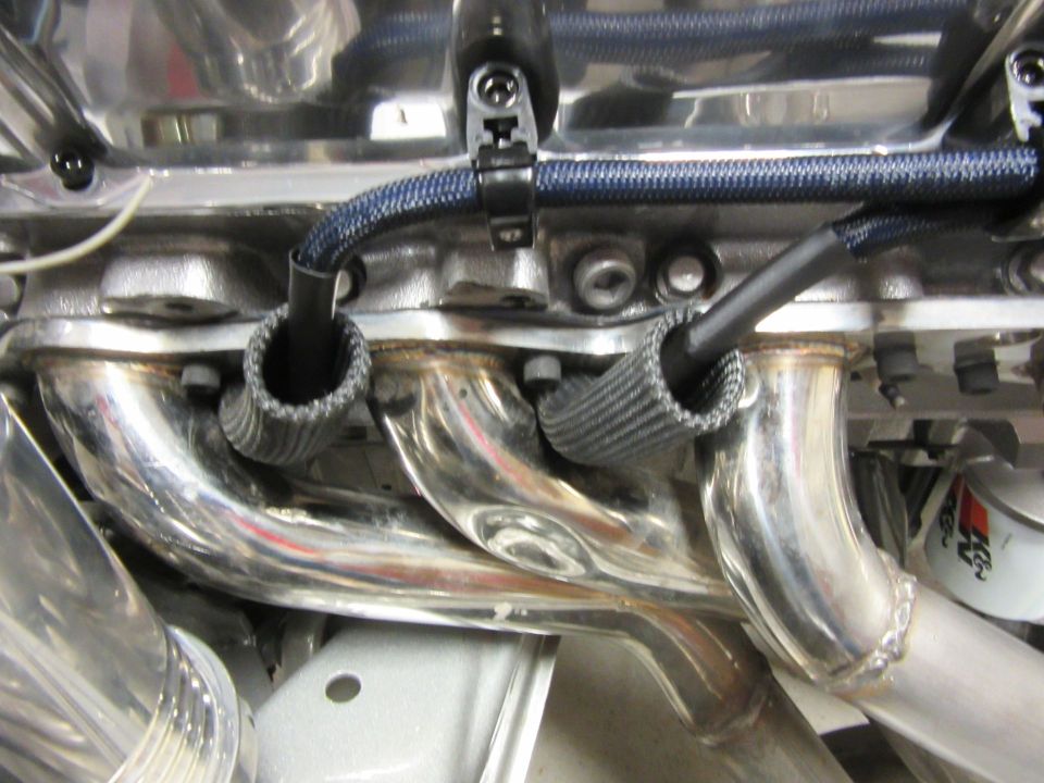 Polished exhaust manifold with heat sleeves on spark plug wires on a V8 engine.