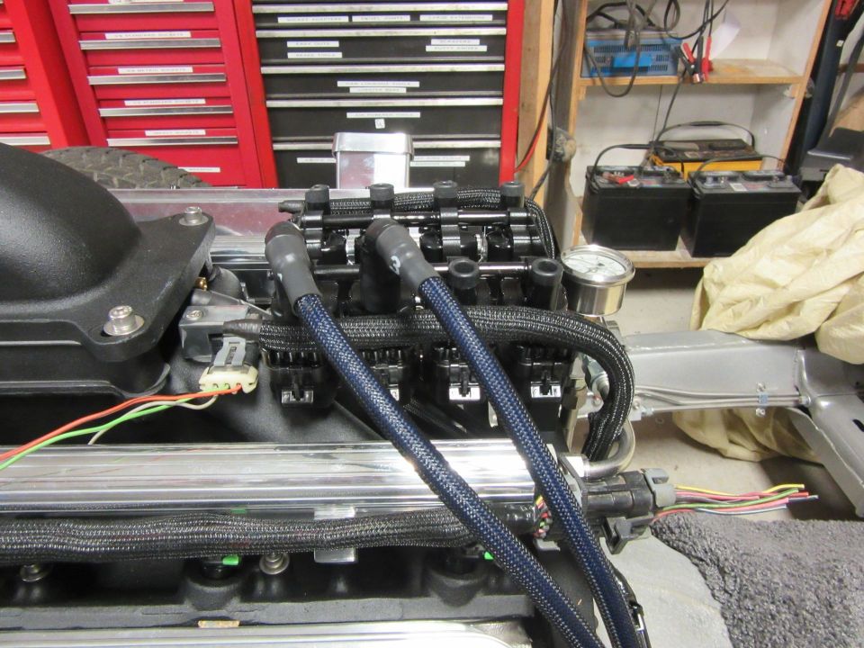 Close-up of a car engine with spark plug wires and fuel injectors.
