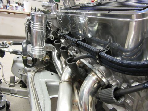 Polished aluminum engine with chrome headers and braided hoses, silver overflow tank.