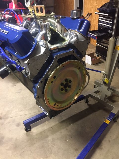 1982 Ford Bronco - A blue and chrome V8 engine is mounted on an engine stand in a garage. The engine features a polished intake manifold, blue valve covers, a…