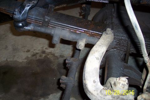 1973 Ford F-250 - A close-up view of the front suspension components of a vehicle, likely a truck, showing a leaf spring, tie rod, and ball joint assembly. T…