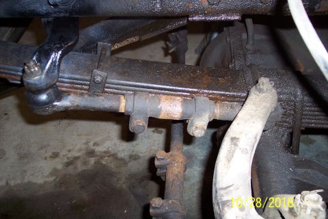 1973 Ford F-250 - A close-up view of the steering linkage and leaf spring assembly on a vintage Ford truck, showing rust and grease.