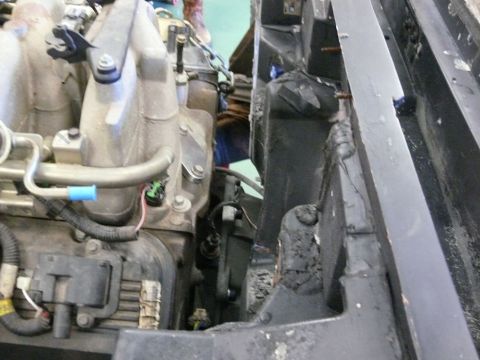Vehicle engine bay with intake manifold, hoses, and wires.