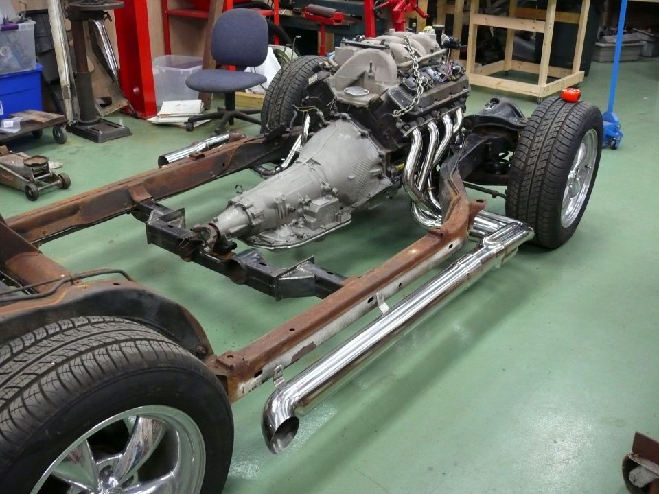 1976 Chevrolet Corvette chassis with V8 engine, transmission, and exhaust system in a workshop.