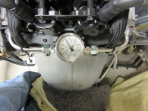 Close-up of a pressure gauge on engine fuel lines.