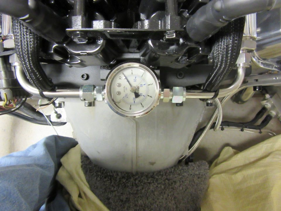 Close-up of a pressure gauge on engine fuel lines.