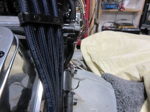 Engine wiring harnesses with black braided loom and a black clamp.