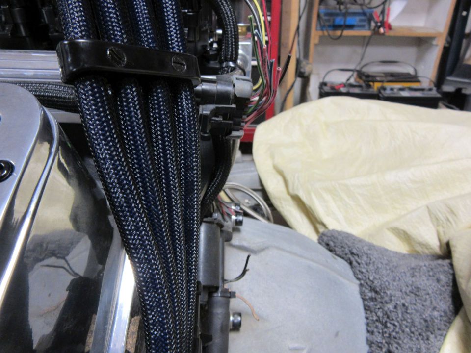 Engine wiring harnesses with black braided loom and a black clamp.
