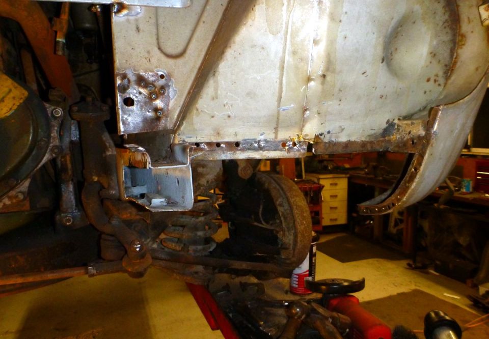 Rusty front fender and suspension components of a vehicle undergoing restoration.