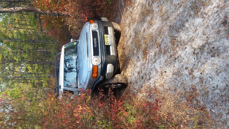 Silver Toyota FJ Cruiser on a sandy trail with fall colors.