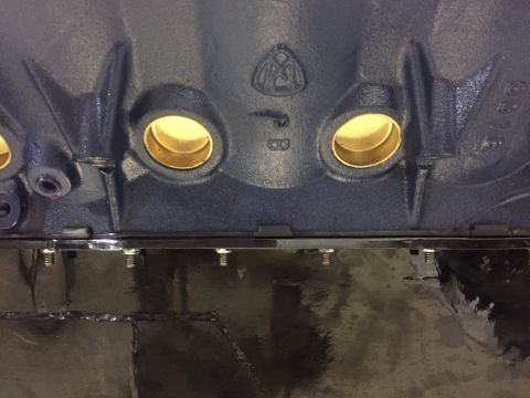 1982 Ford Bronco - A close-up view of the main bearing journals on a dark blue engine block. The journals are lined with brass inserts, and there is a "PB" st…