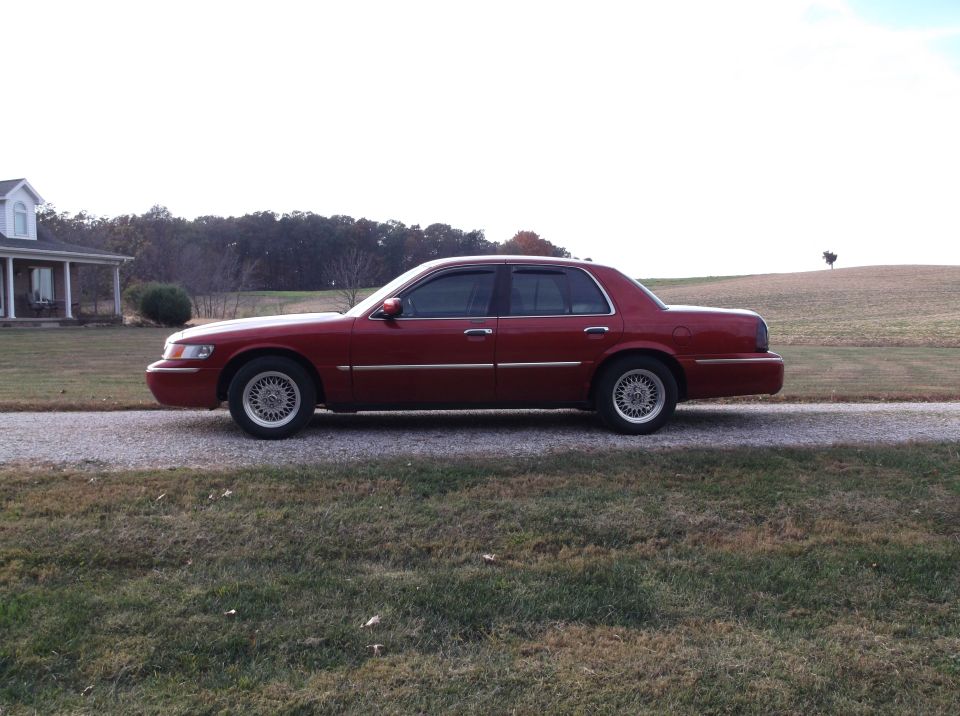 Maroon 1999 Mercury Grand Marquis sedan parked on a gravel driveway.