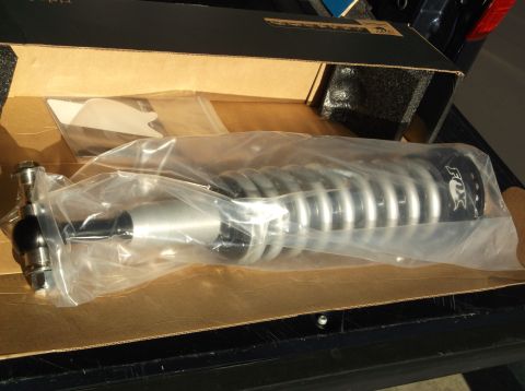 2005 Ford F-150 - A new FOX brand shock absorber with a silver coilover spring is shown inside its original packaging, resting in a cardboard box.