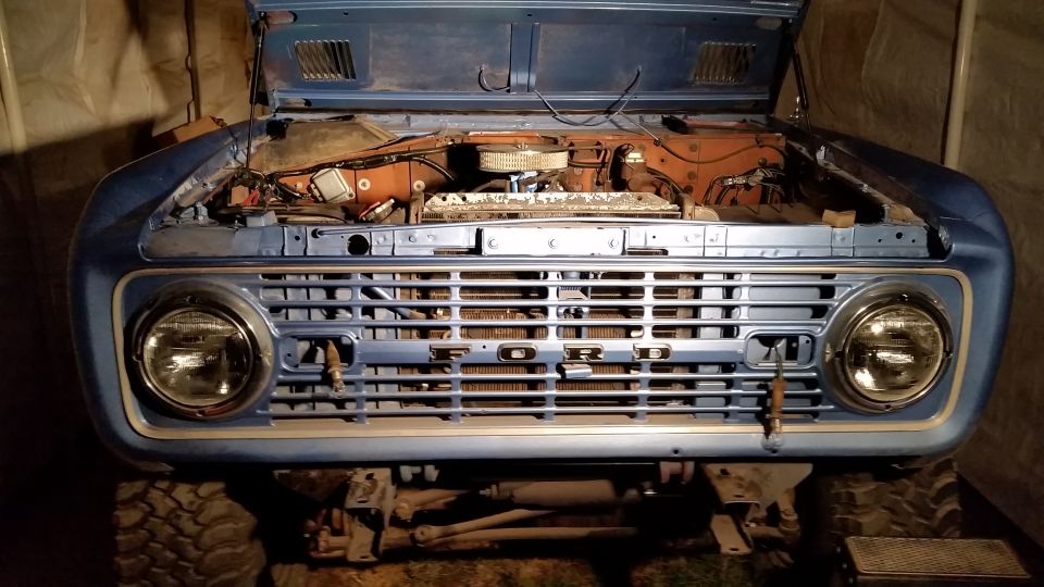 1973 Ford Bronco front view, hood open, blue exterior, silver grille with FORD lettering.