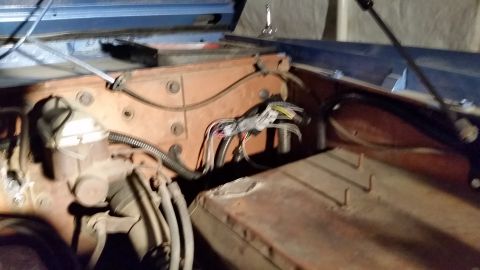 1973 Ford Bronco - The engine bay of a classic Ford Bronco shows the firewall with wiring harnesses and a brake fluid reservoir. The vehicle appears to be und…