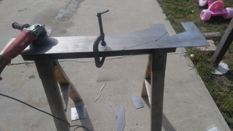 1991 Ford Bronco - Metal is being prepared for cutting with an angle grinder and clamp on a sawhorse outdoors.
