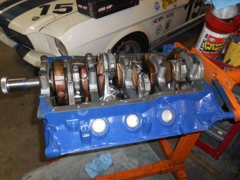 1972 Ford Bronco - A blue engine block with a crankshaft is displayed in front of a white race car.