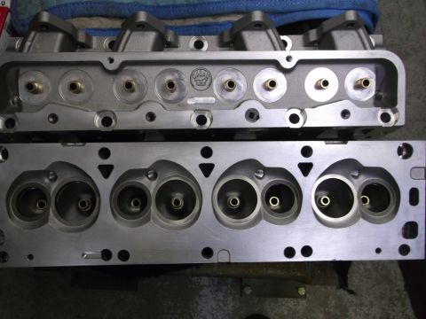 1967 Ford Galaxie - Two aluminum engine cylinder heads are shown, one above the other, revealing the intake and exhaust ports.