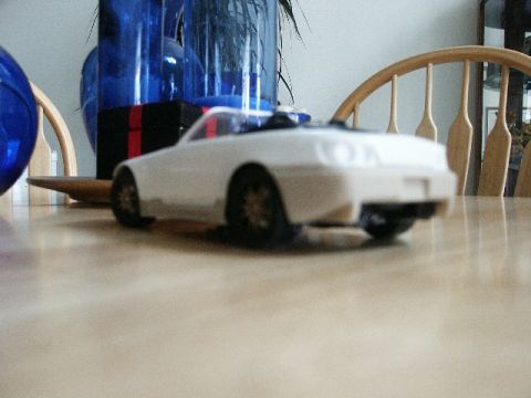 1998 Mercury Sable - A white toy car is positioned on a table, with decorative blue vases and wooden chairs visible behind it.