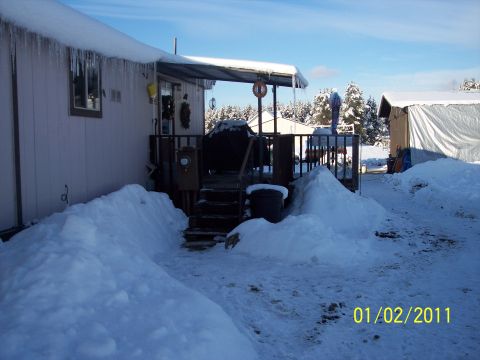 1989 Ford Bronco - Winter scene with snowdrifts and icicles on a house and deck. A shed is visible in the background.