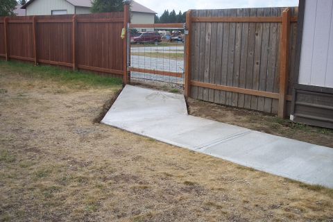 1989 Ford Bronco - A red SUV is visible in the distance behind a wooden fence and gate.