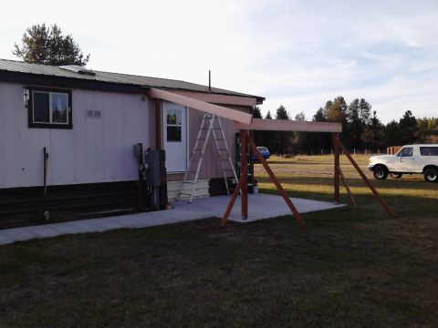 1989 Ford Bronco - A white SUV is parked near a mobile home where a patio cover is being built.